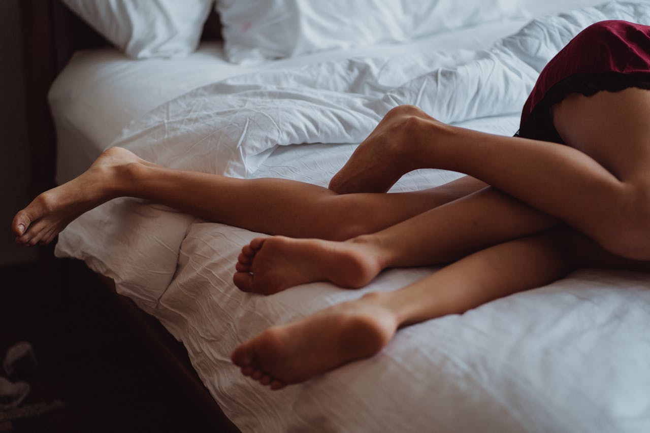 A close-up of intertwined legs illustrating intimacy and relaxation on a bed.